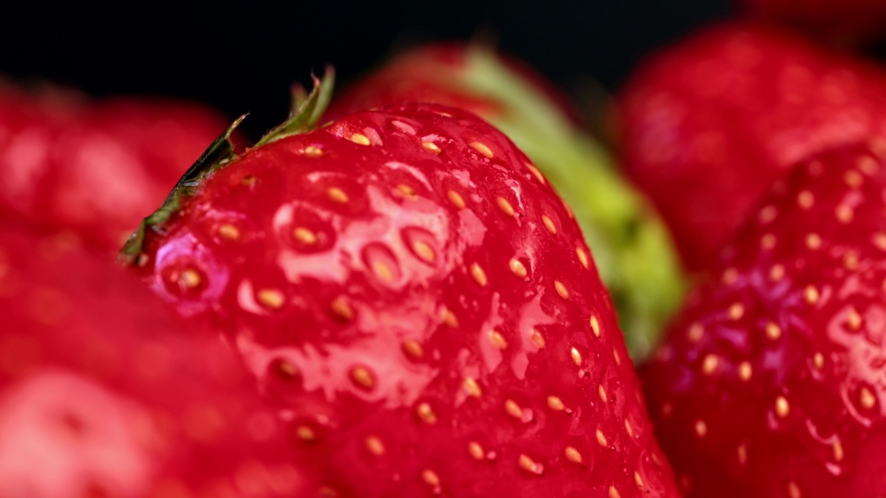 开胃季节性新鲜草莓堆种子和绿叶特写宏跟踪镜头视频素材